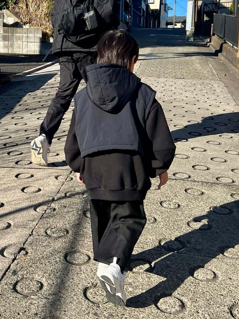 ブラック系のダウンベスト、ブラック系のスウェット、ブラック系のパンツを着用したキッズの冬コーディネートの3枚目の写真