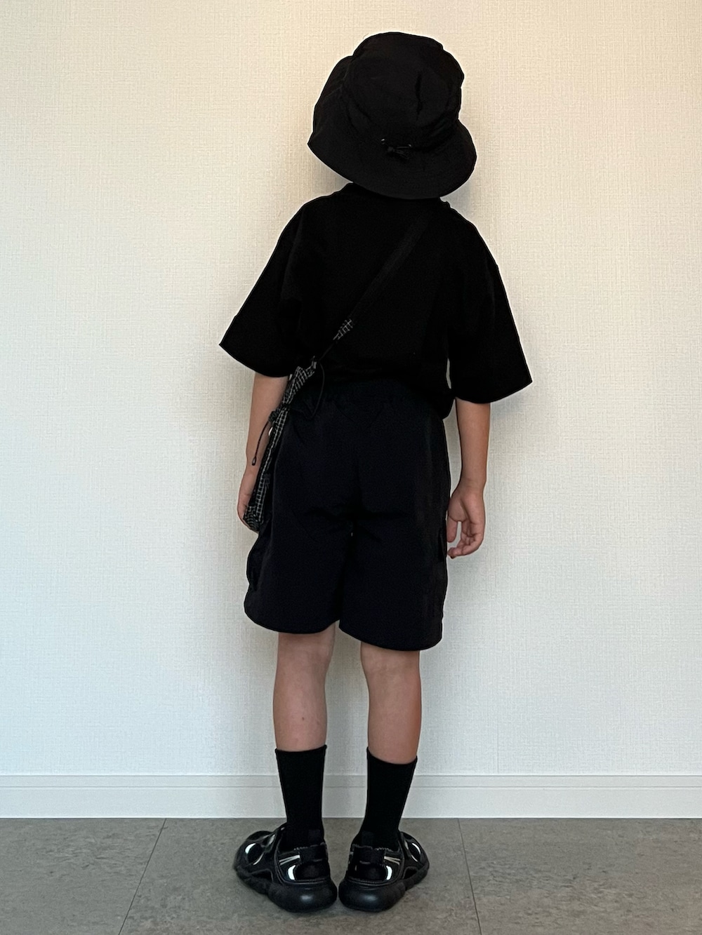 ブラック系のショルダーバッグ、ブラック系のパンツ、ブラック系のサンダルを着用したキッズの夏コーディネートの3枚目の写真