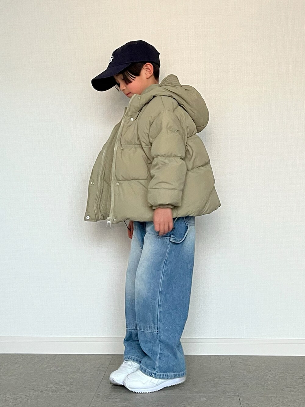 グリーン系のダウンジャケット/コート、ホワイト系のTシャツ/カットソー、ブルー系のデニムパンツを着用したキッズの春コーディネートの2枚目の写真