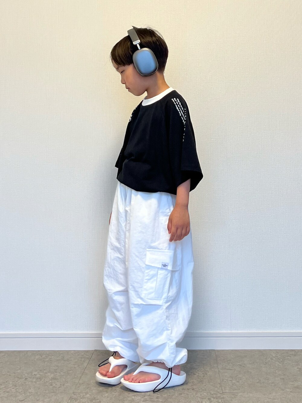 ブラック系のTシャツ/カットソー、ホワイト系のカーゴパンツ、ホワイト系のサンダルを着用したキッズの夏コーディネートの2枚目の写真