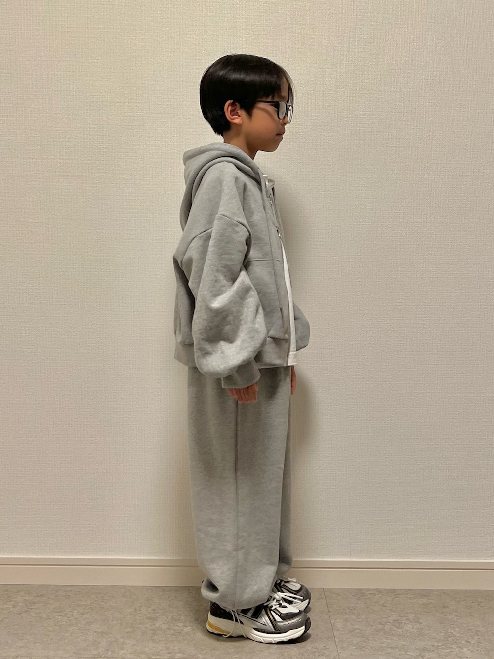 グレー系のスウェットパンツ、ホワイト系のスニーカー、グレー系のパーカーを着用したキッズの秋コーディネートの3枚目の写真