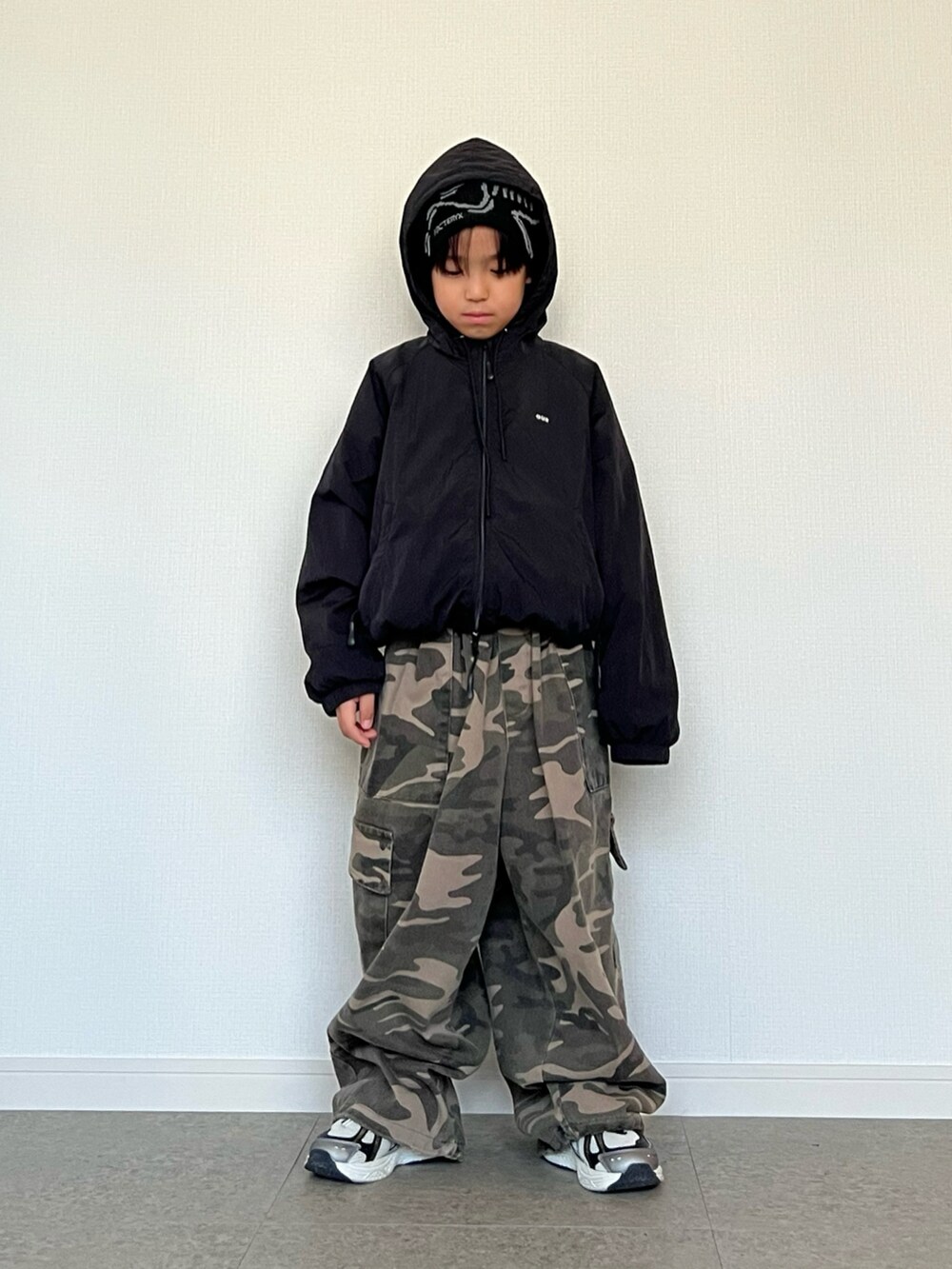 グリーン系のカーゴパンツ、ホワイト系のスニーカー、ブラック系のナイロンジャケットを着用したキッズの冬コーディネートの2枚目の写真