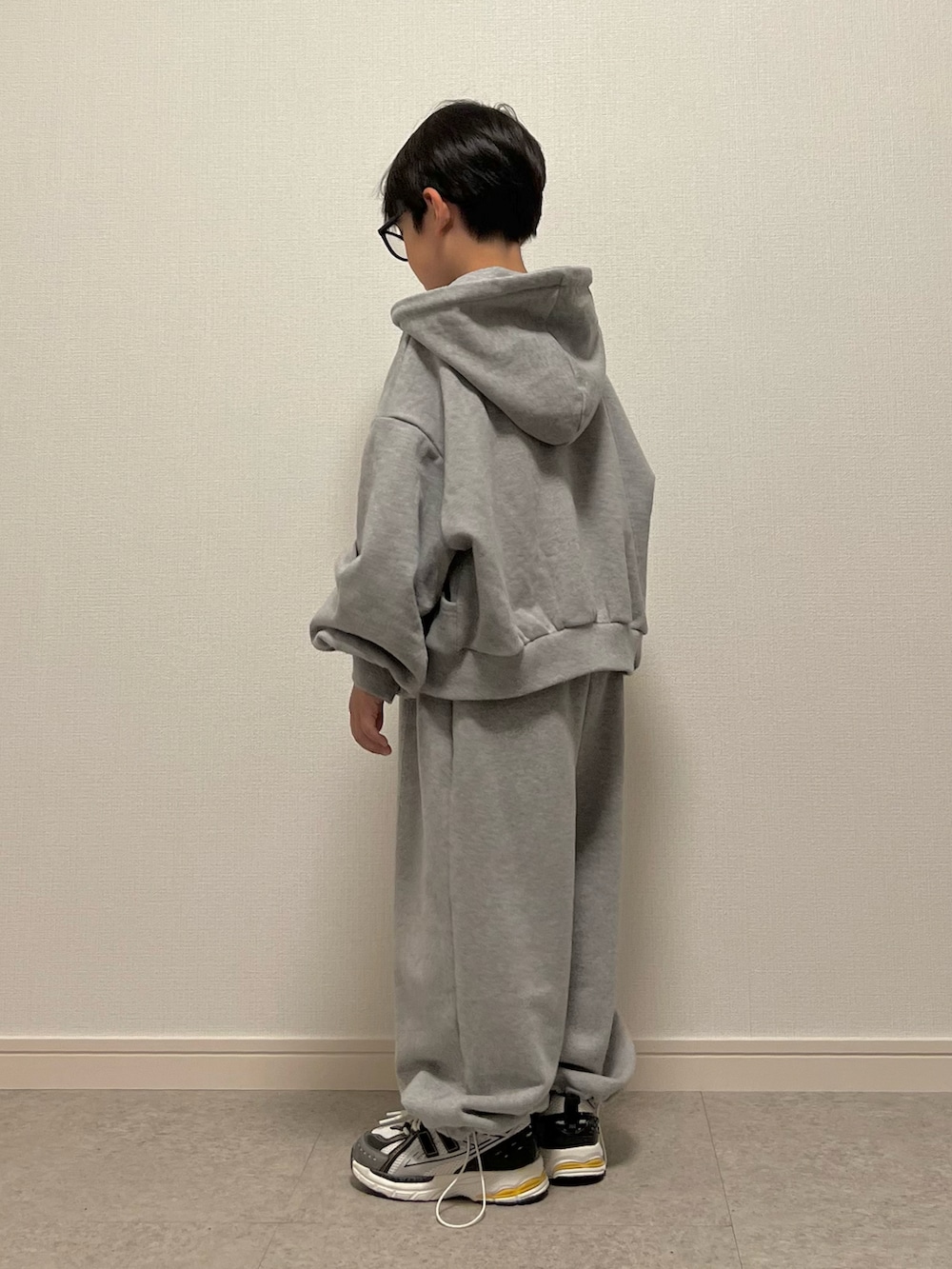 グレー系のスウェットパンツ、ホワイト系のスニーカー、グレー系のパーカーを着用したキッズの秋コーディネートの2枚目の写真