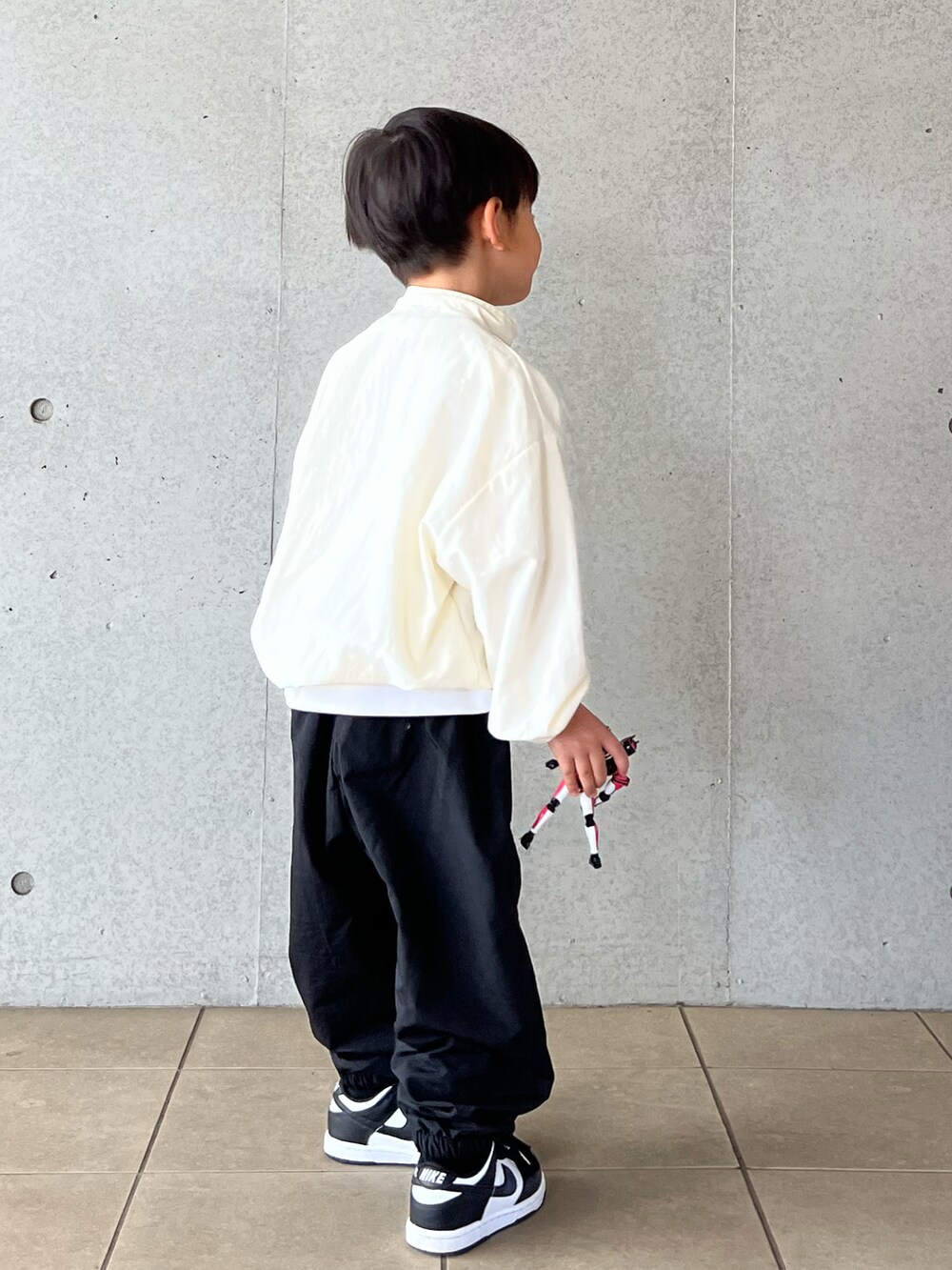 ブラック系のパンツ、ホワイト系のベスト、ホワイト系のTシャツ/カットソーを着用したキッズの春コーディネートの3枚目の写真