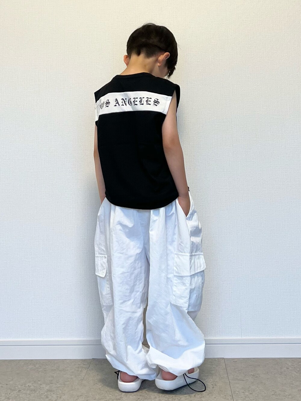 ホワイト系のカーゴパンツ、ブラック系のタンクトップ、ホワイト系のサンダルを着用したキッズの夏コーディネートの4枚目の写真