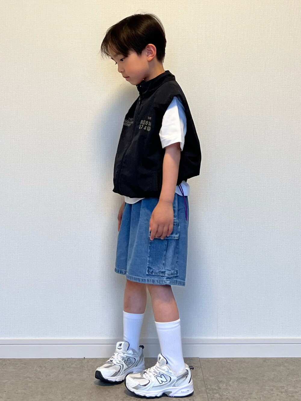 ブラック系のベスト、ホワイト系のTシャツ/カットソー、ホワイト系のスニーカーを着用したキッズの春コーディネートの2枚目の写真