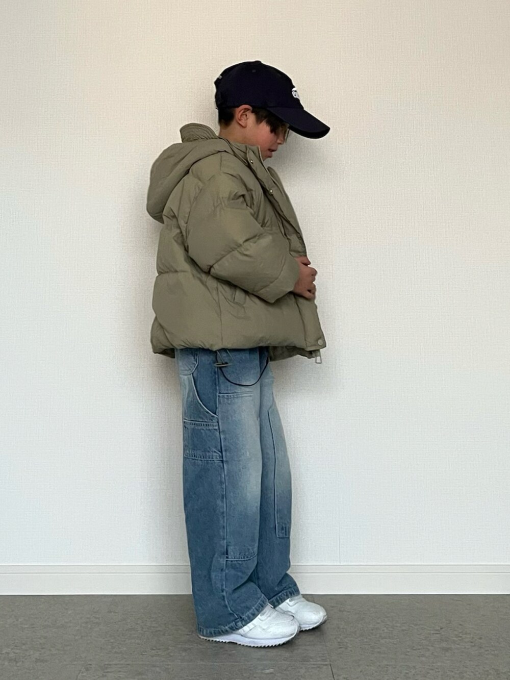 グリーン系のダウンジャケット/コート、ホワイト系のTシャツ/カットソー、ブルー系のデニムパンツを着用したキッズの春コーディネートの4枚目の写真