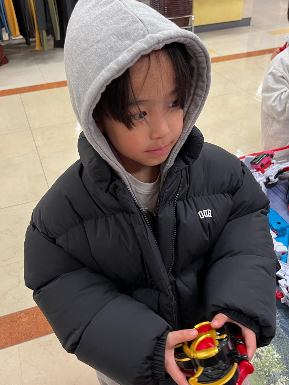 ブラック系のダウンジャケット/コート、グレー系のパーカー、グレー系のスウェットパンツを着用したキッズの冬コーディネートの3枚目の写真