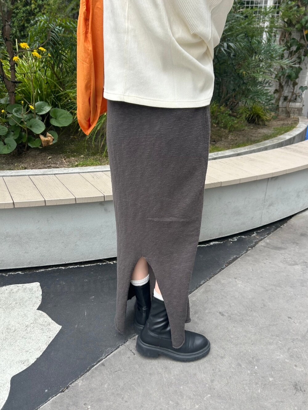 グレー系のスカート、ホワイト系のTシャツ/カットソー、オレンジ系のエコバッグ/サブバッグを着用したレディースの冬コーディネートの5枚目の写真