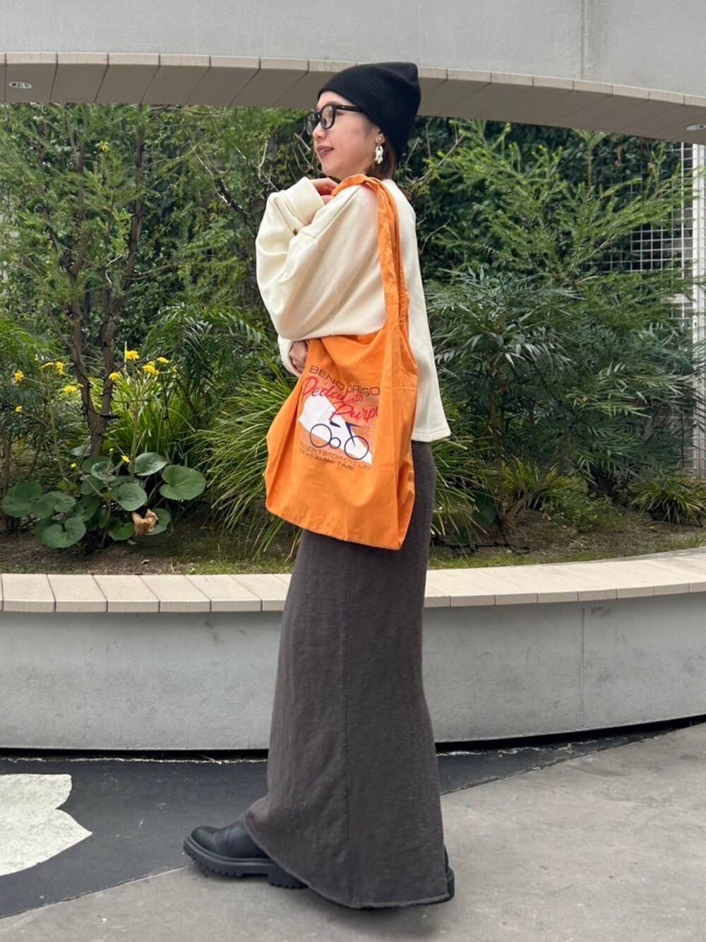 グレー系のスカート、ホワイト系のTシャツ/カットソー、オレンジ系のエコバッグ/サブバッグを着用したレディースの冬コーディネートの2枚目の写真