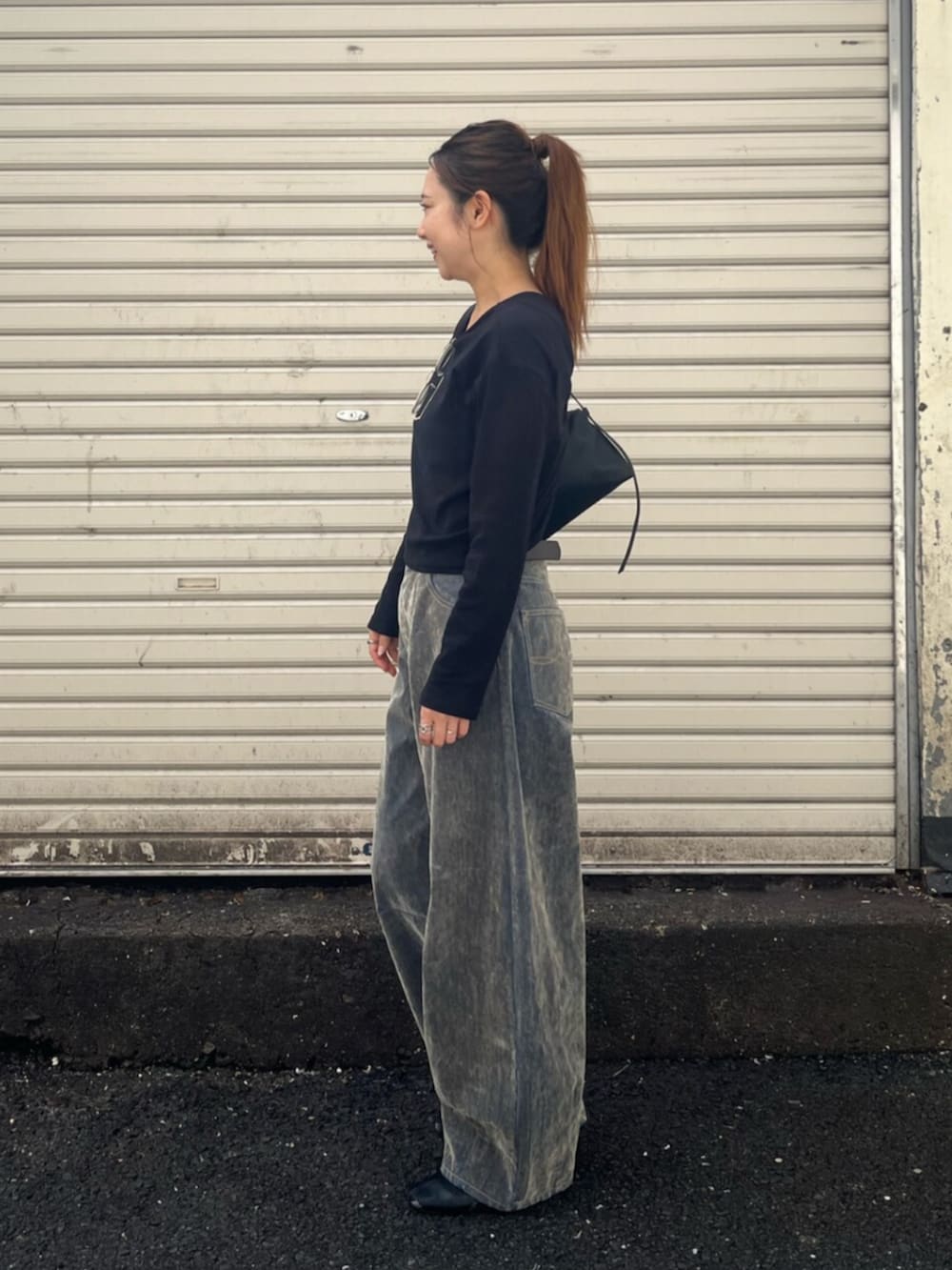 ベージュ系のデニムパンツ、ブラック系のTシャツ/カットソー、ブラック系のハンドバッグを着用したレディースの秋コーディネートの3枚目の写真