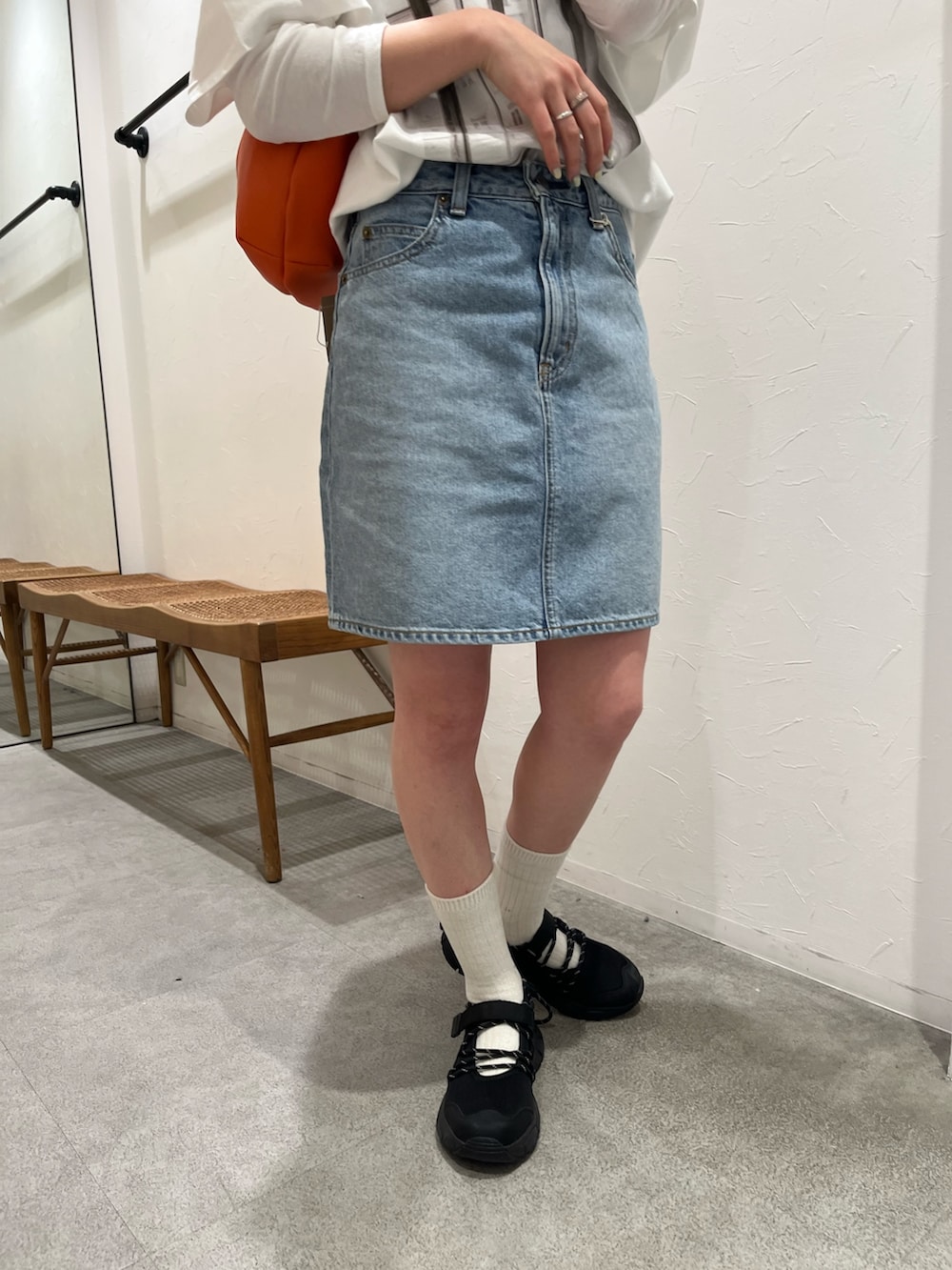 ホワイト系のTシャツ/カットソー、ブルー系のスカート、ブラック系のスニーカーを着用したレディースの春コーディネートの5枚目の写真