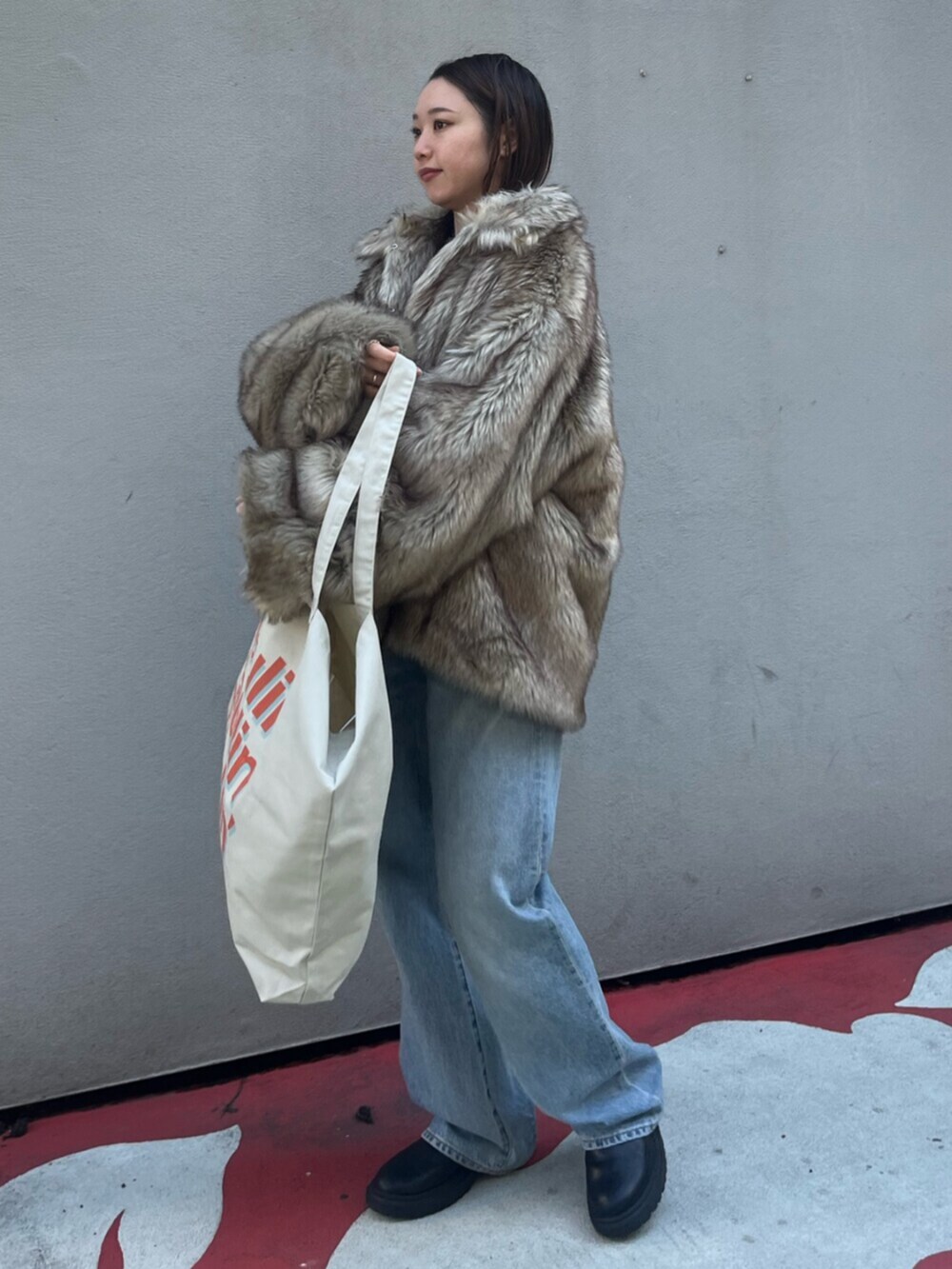 ブルー系のデニムパンツ、ベージュ系のダウンジャケット/コート、ホワイト系のトートバッグを着用したレディースの冬コーディネートの2枚目の写真