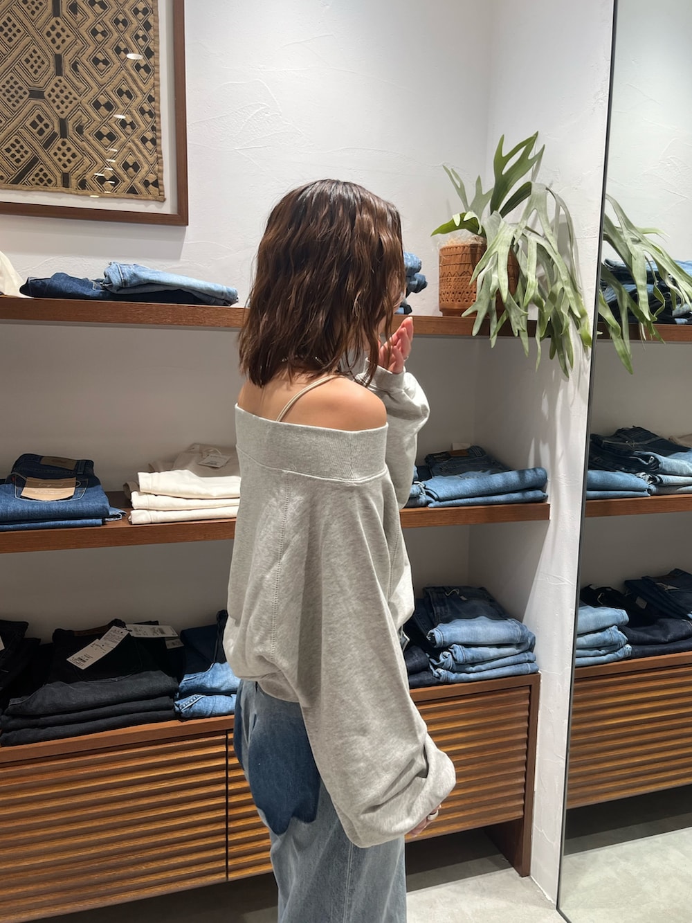 グレー系のスウェット、ホワイト系のキャミソール、ブルー系のデニムパンツを着用したレディースの秋コーディネートの4枚目の写真