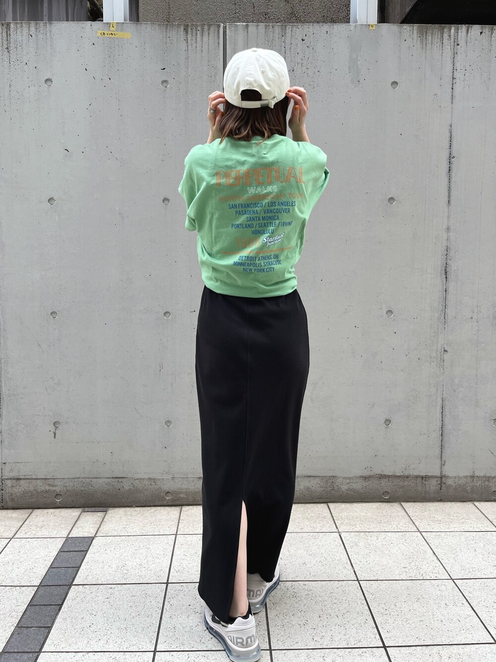 グリーン系のTシャツ/カットソー、ブラック系のワンピース、ホワイト系のキャップを着用したレディースの夏コーディネートの3枚目の写真