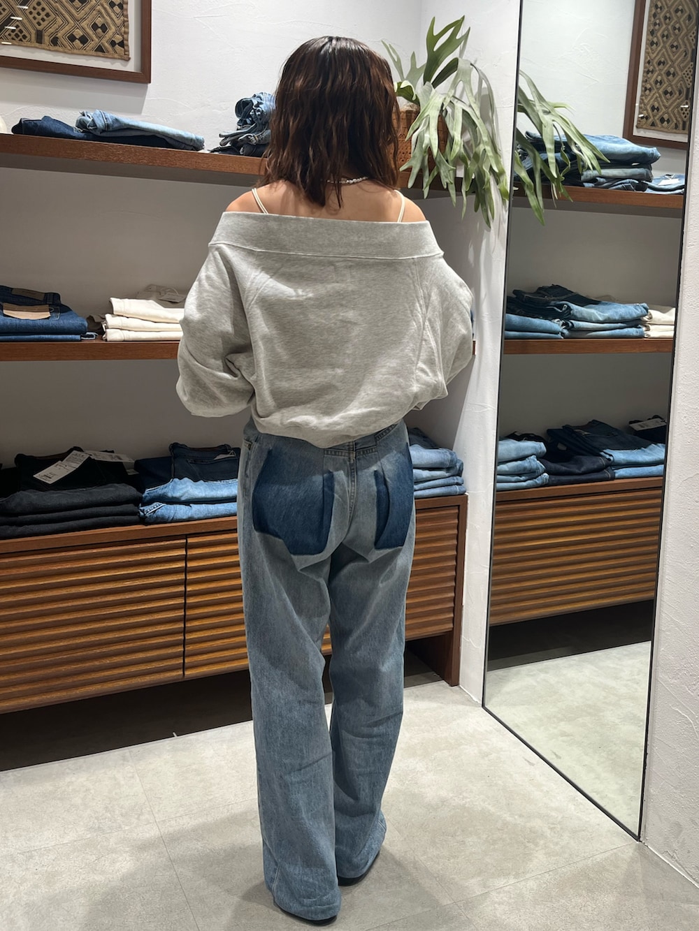 グレー系のスウェット、ホワイト系のキャミソール、ブルー系のデニムパンツを着用したレディースの秋コーディネートの3枚目の写真