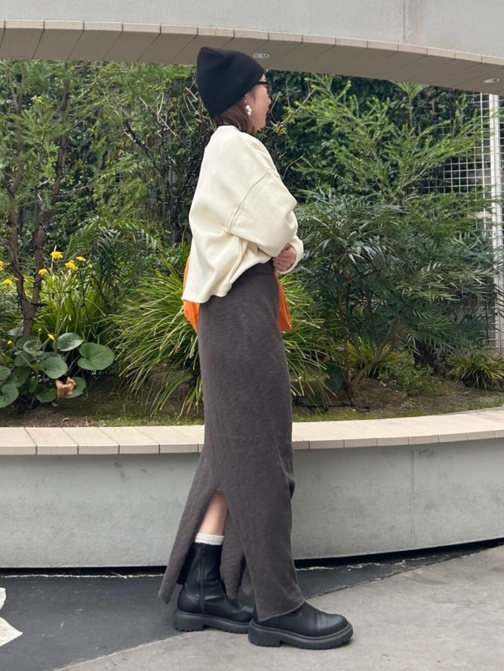 グレー系のスカート、ホワイト系のTシャツ/カットソー、オレンジ系のエコバッグ/サブバッグを着用したレディースの冬コーディネートの3枚目の写真