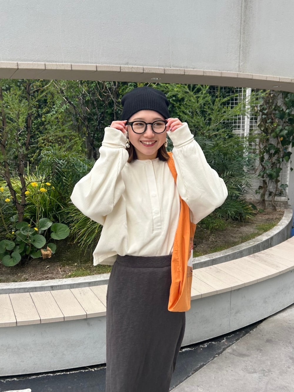 グレー系のスカート、ホワイト系のTシャツ/カットソー、オレンジ系のエコバッグ/サブバッグを着用したレディースの冬コーディネートの6枚目の写真