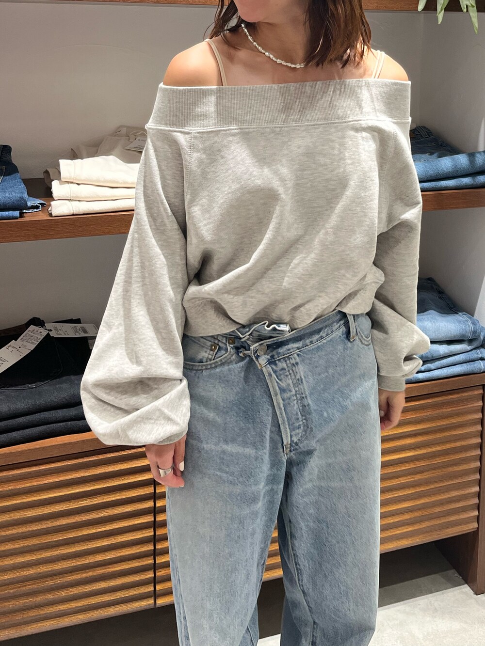 グレー系のスウェット、ホワイト系のキャミソール、ブルー系のデニムパンツを着用したレディースの秋コーディネートの5枚目の写真