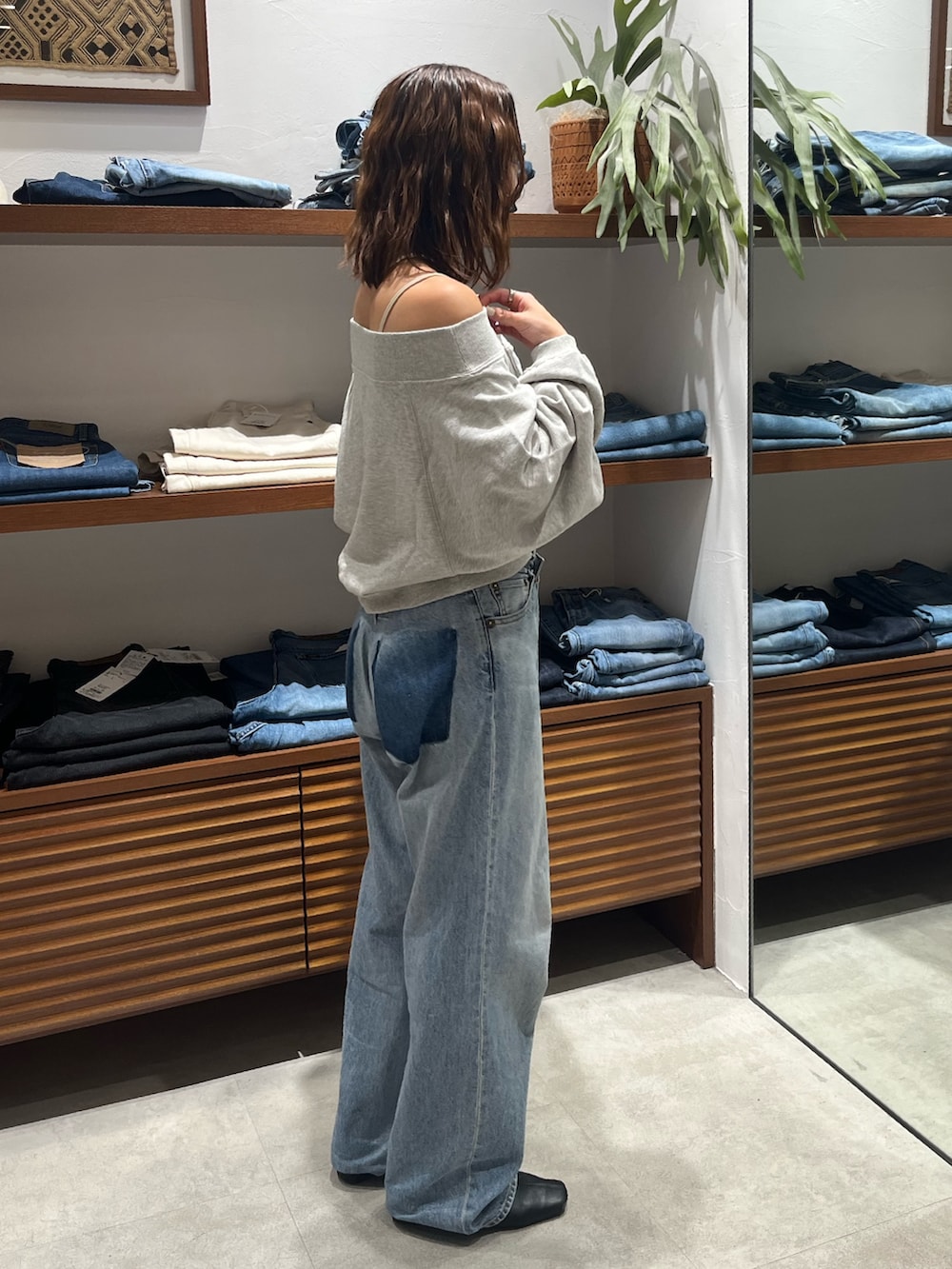 グレー系のスウェット、ホワイト系のキャミソール、ブルー系のデニムパンツを着用したレディースの秋コーディネートの2枚目の写真