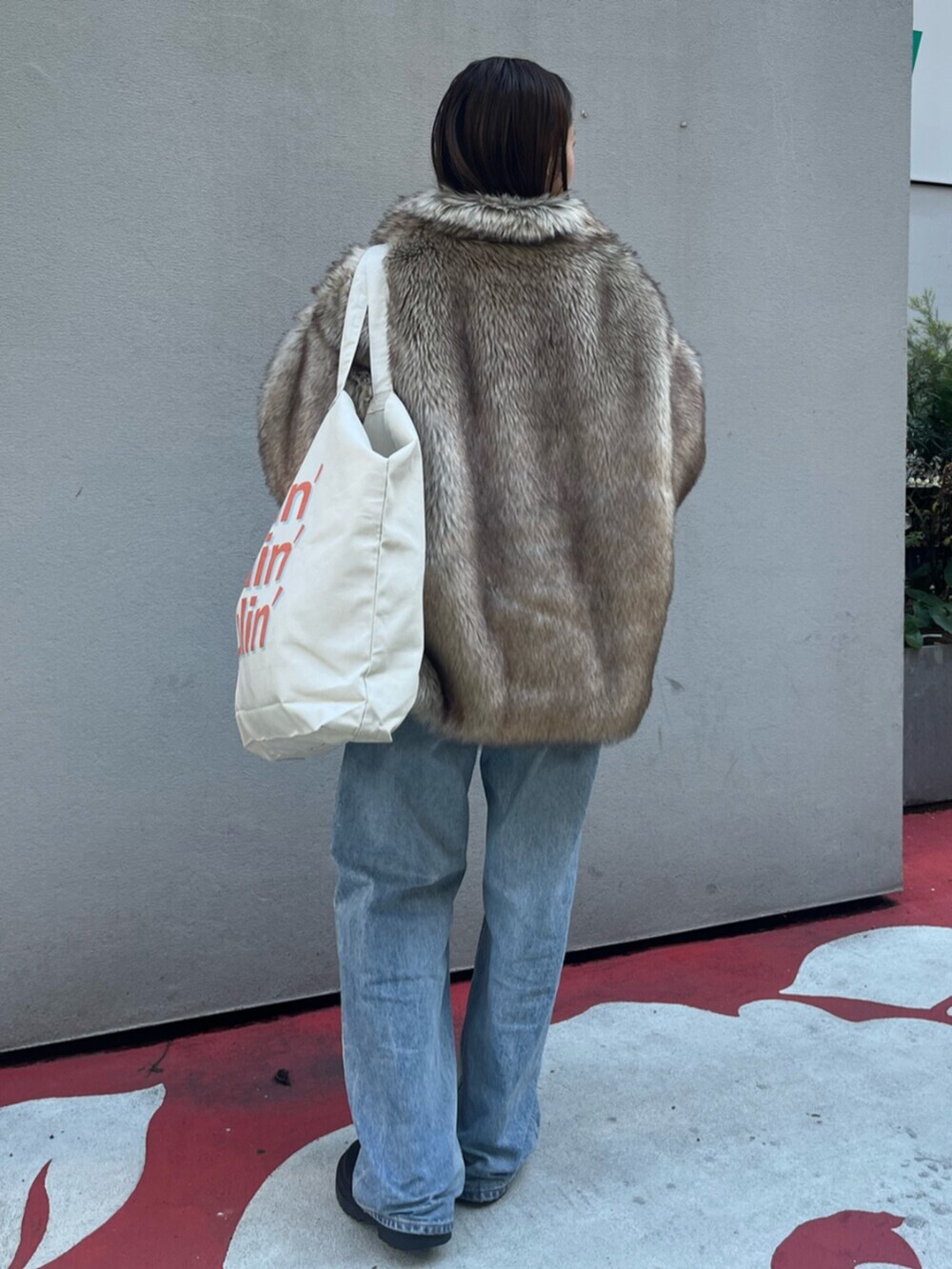 ブルー系のデニムパンツ、ベージュ系のダウンジャケット/コート、ホワイト系のトートバッグを着用したレディースの冬コーディネートの3枚目の写真