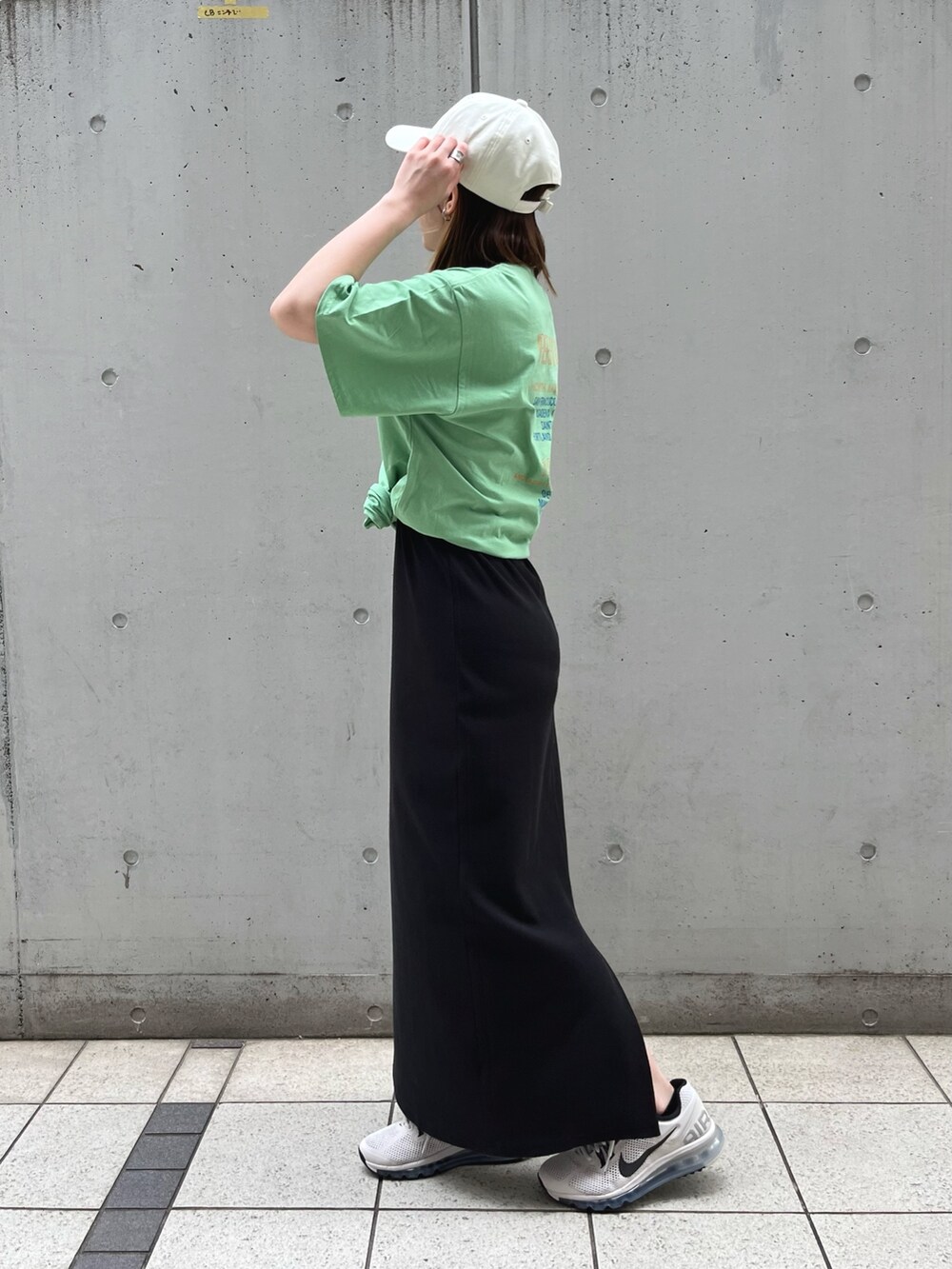 グリーン系のTシャツ/カットソー、ブラック系のワンピース、ホワイト系のキャップを着用したレディースの夏コーディネートの2枚目の写真