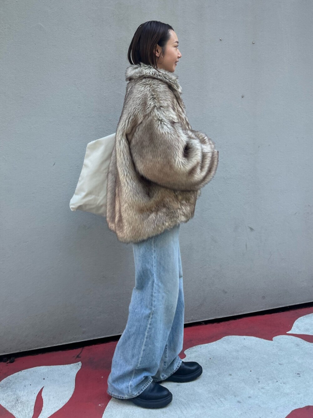 ブルー系のデニムパンツ、ベージュ系のダウンジャケット/コート、ホワイト系のトートバッグを着用したレディースの冬コーディネートの4枚目の写真