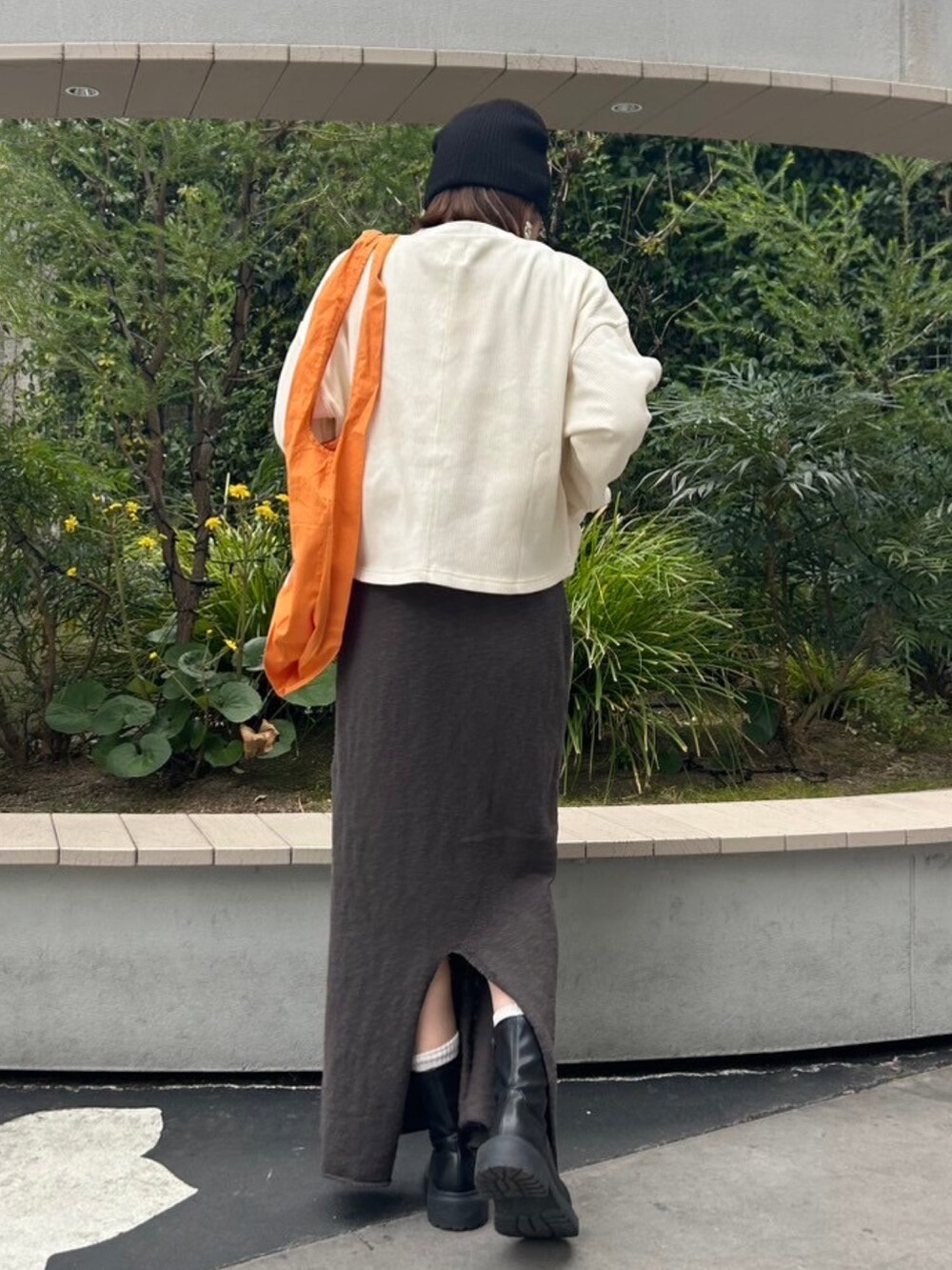グレー系のスカート、ホワイト系のTシャツ/カットソー、オレンジ系のエコバッグ/サブバッグを着用したレディースの冬コーディネートの4枚目の写真
