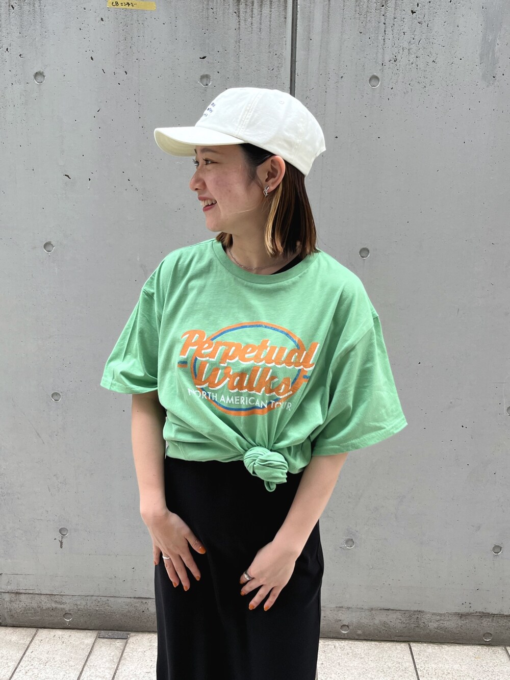 グリーン系のTシャツ/カットソー、ブラック系のワンピース、ホワイト系のキャップを着用したレディースの夏コーディネートの4枚目の写真