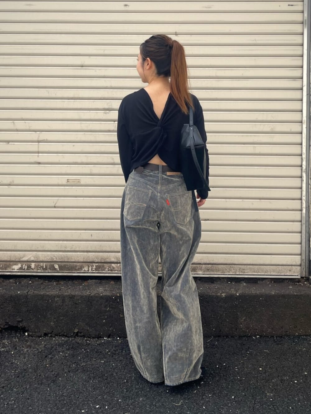 ベージュ系のデニムパンツ、ブラック系のTシャツ/カットソー、ブラック系のハンドバッグを着用したレディースの秋コーディネートの2枚目の写真