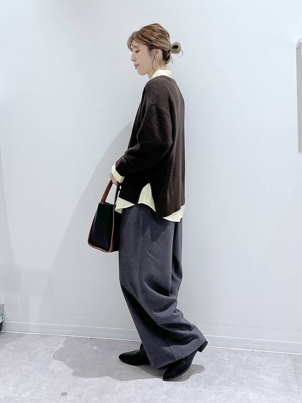 イエロー系のシャツ/ブラウス、ブラウン系のニット/セーター、ブラック系のトートバッグを着用したレディースの冬コーディネートの2枚目の写真