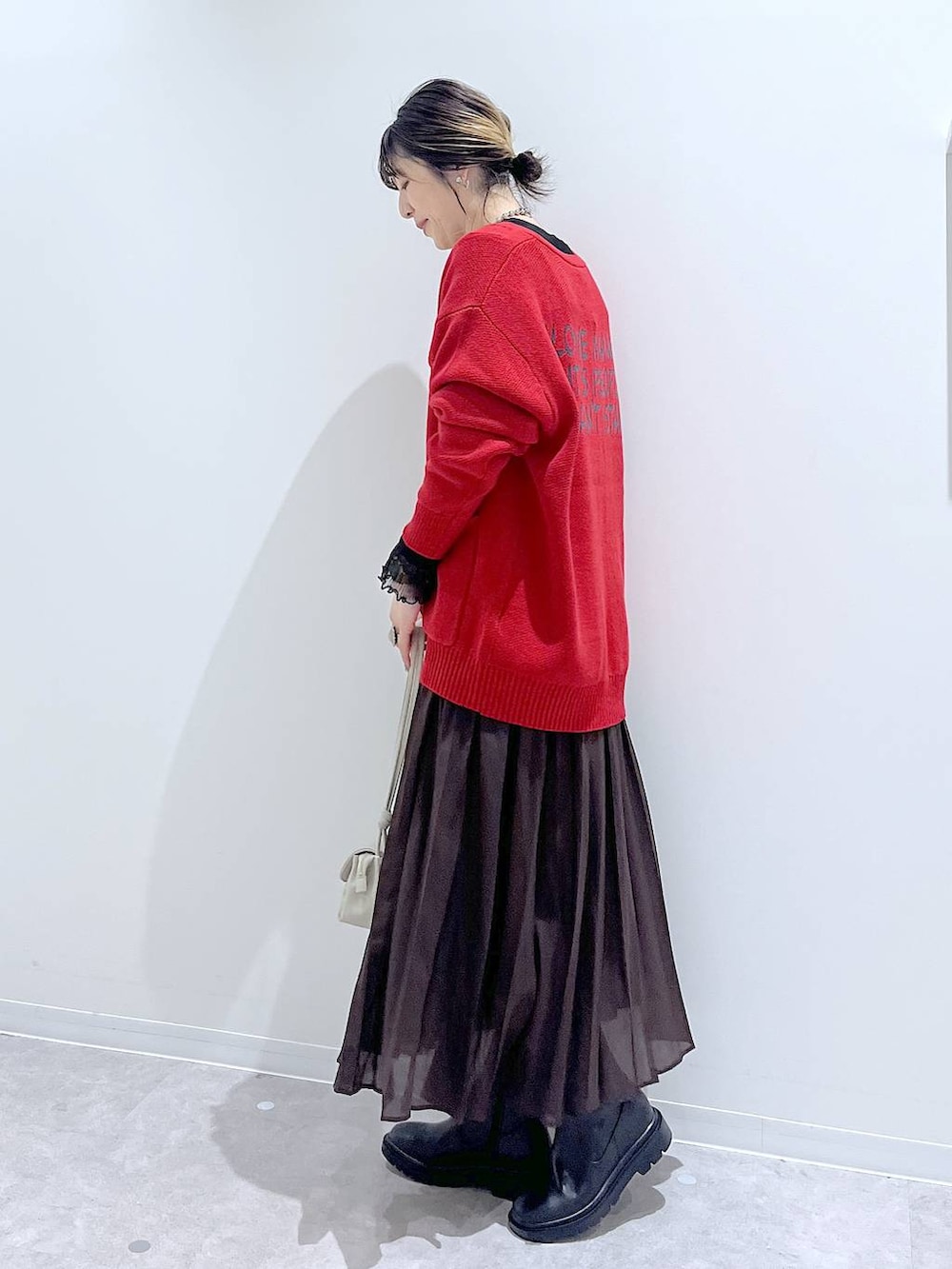 ブラウン系のスカート、ベージュ系のショルダーバッグ、ブラック系のTシャツ/カットソーを着用したレディースの秋コーディネートの2枚目の写真