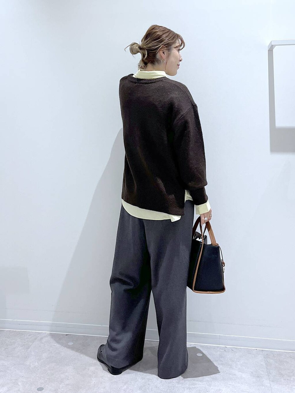 イエロー系のシャツ/ブラウス、ブラウン系のニット/セーター、ブラック系のトートバッグを着用したレディースの冬コーディネートの3枚目の写真