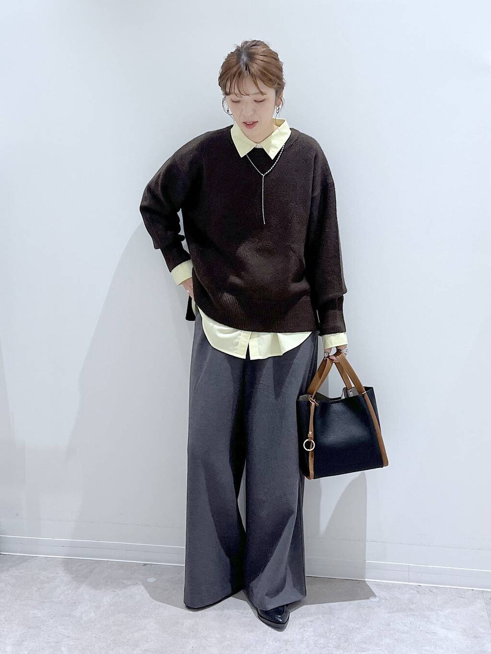 イエロー系のシャツ/ブラウス、ブラウン系のニット/セーター、ブラック系のトートバッグを着用したレディースの冬コーディネートの4枚目の写真