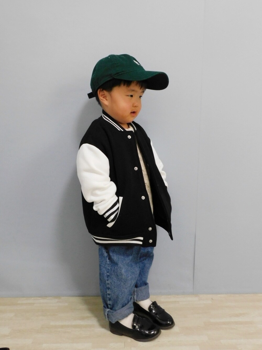 ブラック系のスタジャン、ブルー系のデニムパンツ、ブラック系のローファーを着用したキッズの冬コーディネートの3枚目の写真
