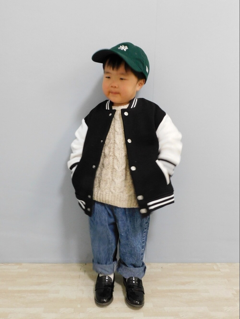 ブラック系のスタジャン、ブルー系のデニムパンツ、ブラック系のローファーを着用したキッズの冬コーディネートの2枚目の写真