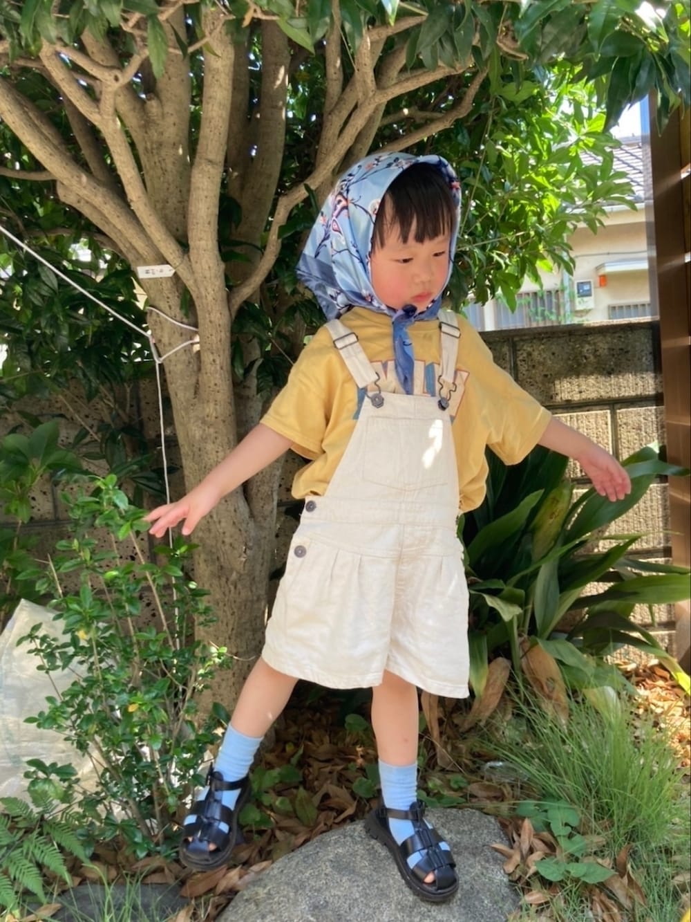イエロー系のTシャツ/カットソー、ホワイト系のサロペット/オーバーオール、ブラック系のサンダルを着用したキッズの秋コーディネートの2枚目の写真