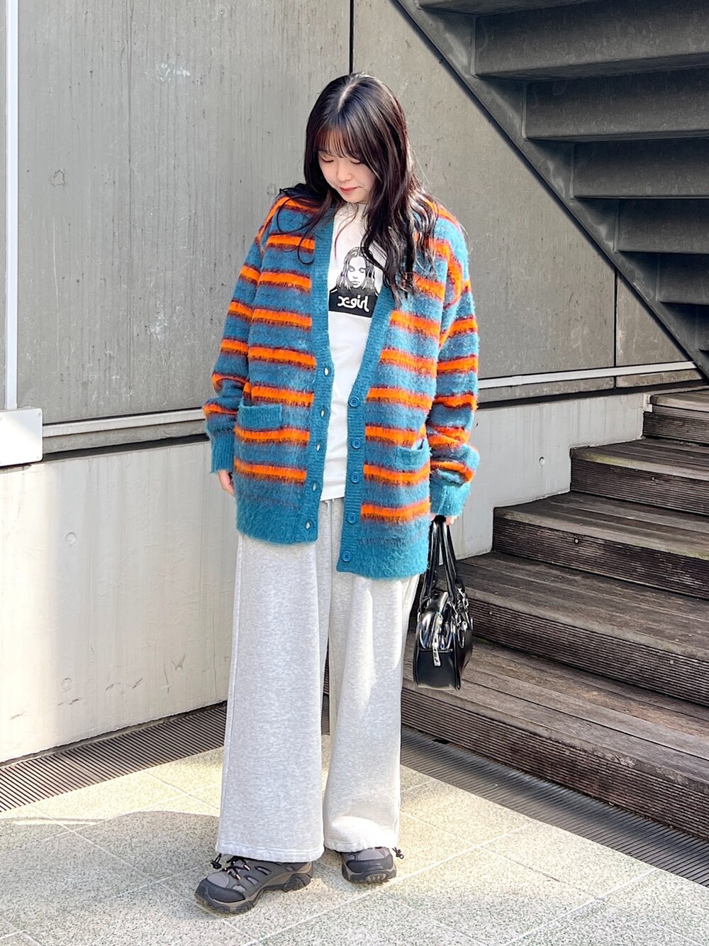 ブルー系のカーディガン/ボレロ、イエロー系のハンドバッグ、グレー系のスウェットパンツを着用したレディースの秋コーディネートの2枚目の写真