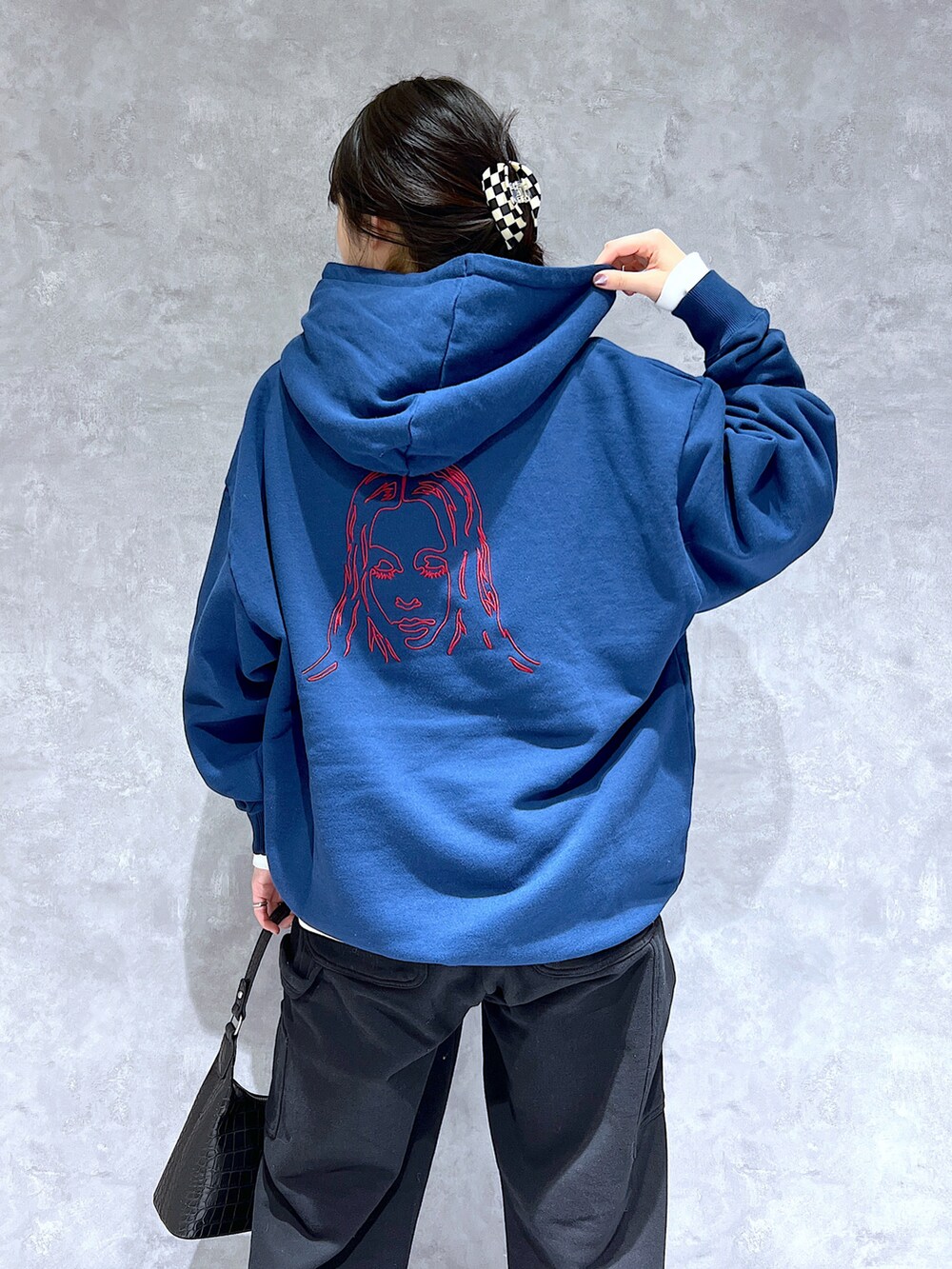 ブラック系のスウェットパンツ、ブルー系のパーカー、ホワイト系のショルダーバッグを着用したレディースの秋コーディネートの2枚目の写真