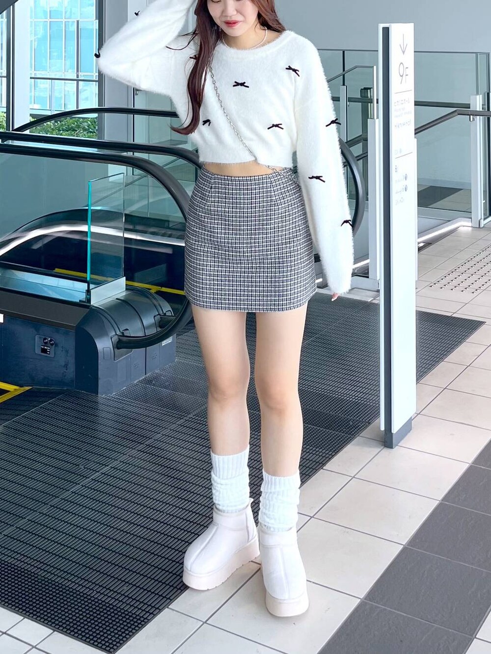 ブラック系のスカート、ホワイト系のニット/セーター、ブラック系のショルダーバッグを着用したレディースの秋コーディネートの3枚目の写真