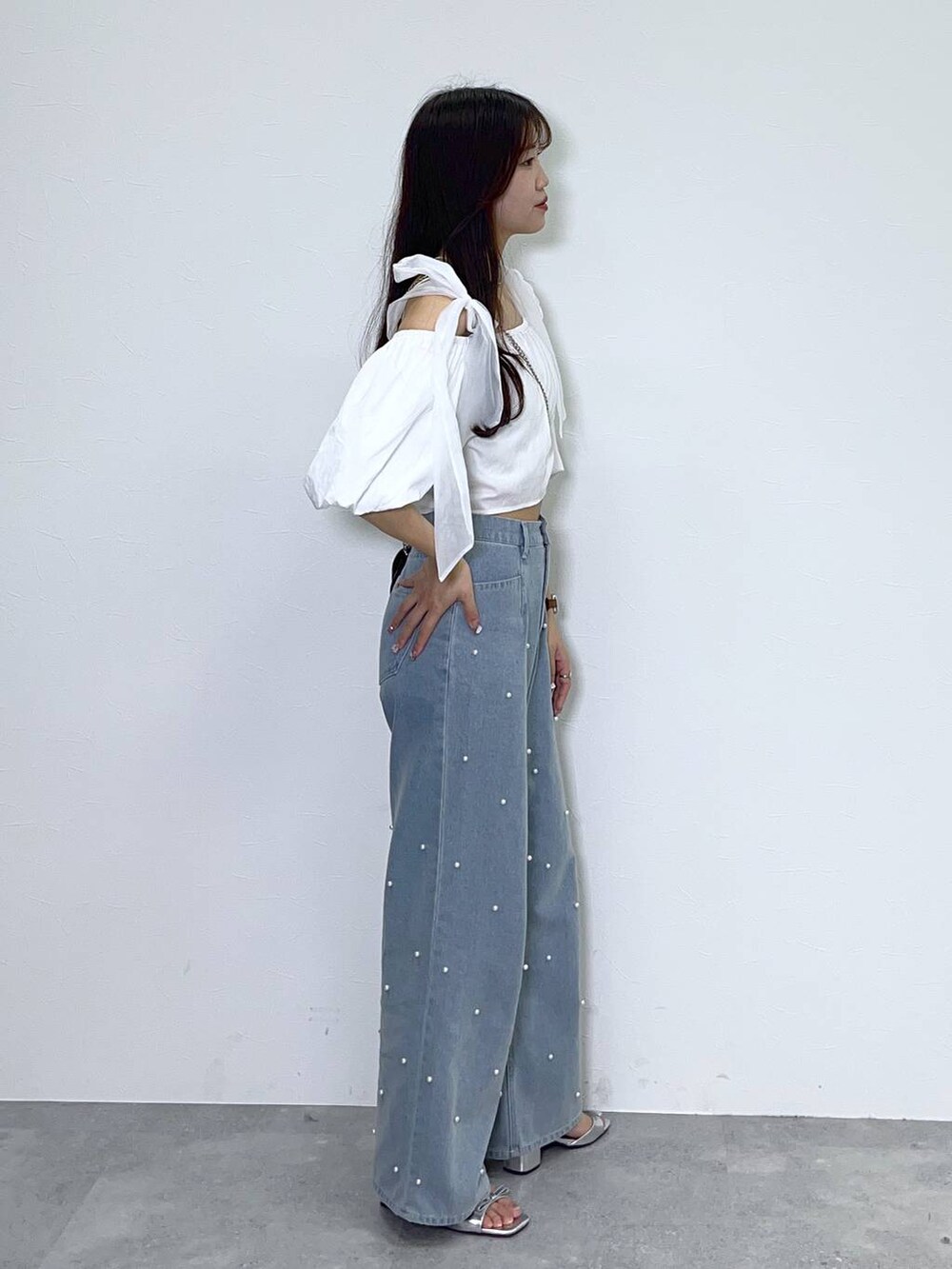 ブラック系のショルダーバッグ、ホワイト系のキャミソール、ブルー系のデニムパンツを着用したレディースの春コーディネートの4枚目の写真