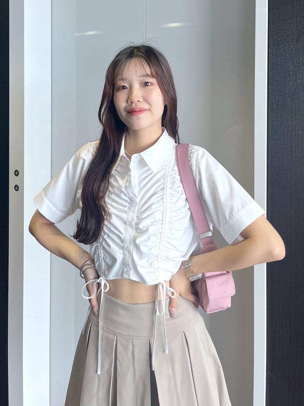 ピンク系のショルダーバッグ、ホワイト系のキャミソール、ベージュ系のスカートを着用したレディースの夏コーディネートの6枚目の写真