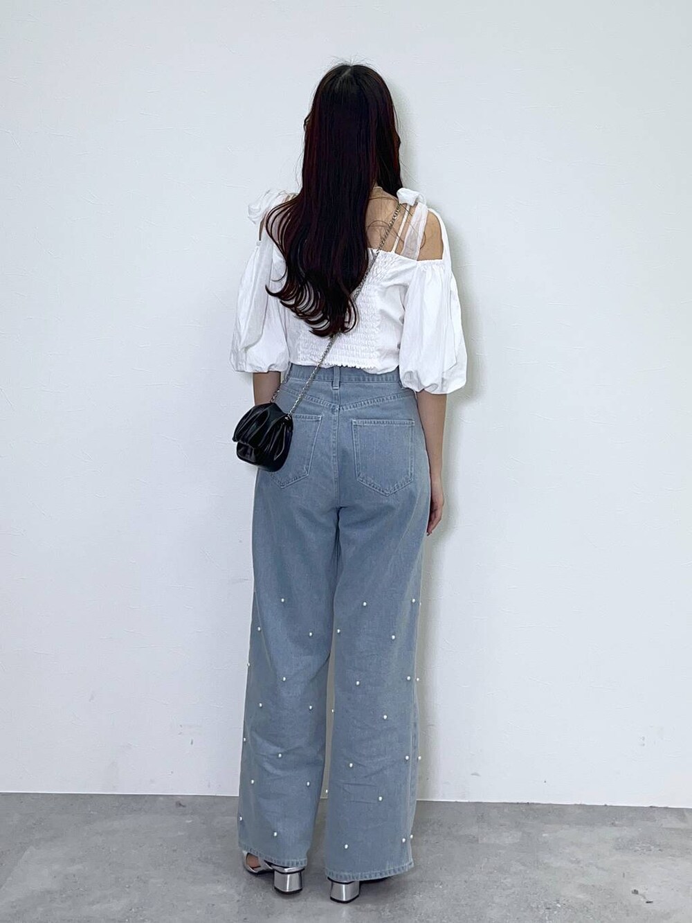 ブラック系のショルダーバッグ、ホワイト系のキャミソール、ブルー系のデニムパンツを着用したレディースの春コーディネートの3枚目の写真