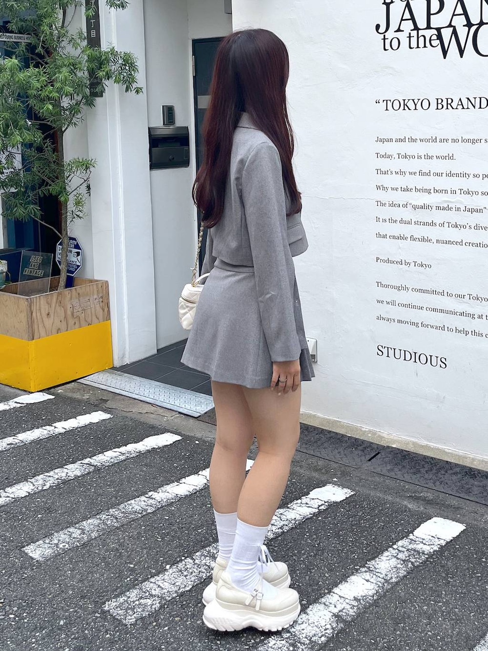 グレー系のテーラードジャケット、ホワイト系のショルダーバッグ、ホワイト系のキャミソールを着用したレディースの夏コーディネートの5枚目の写真