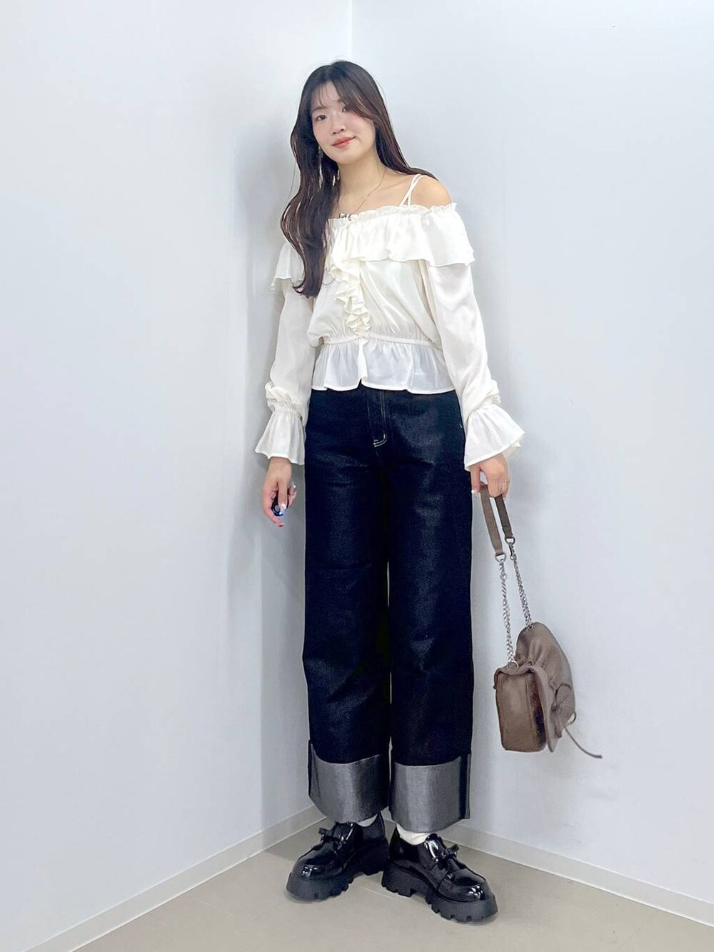 ブラウン系のショルダーバッグ、ホワイト系のキャミソール、ブラック系のドレスシューズを着用したレディースの冬コーディネートの2枚目の写真