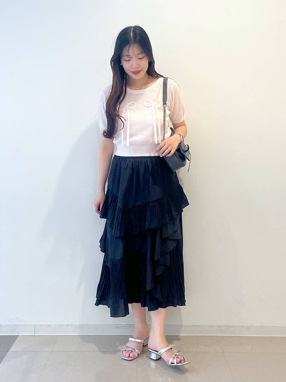 グレー系のショルダーバッグ、ホワイト系のキャミソール、ブラック系のスカートを着用したレディースの春コーディネートの6枚目の写真