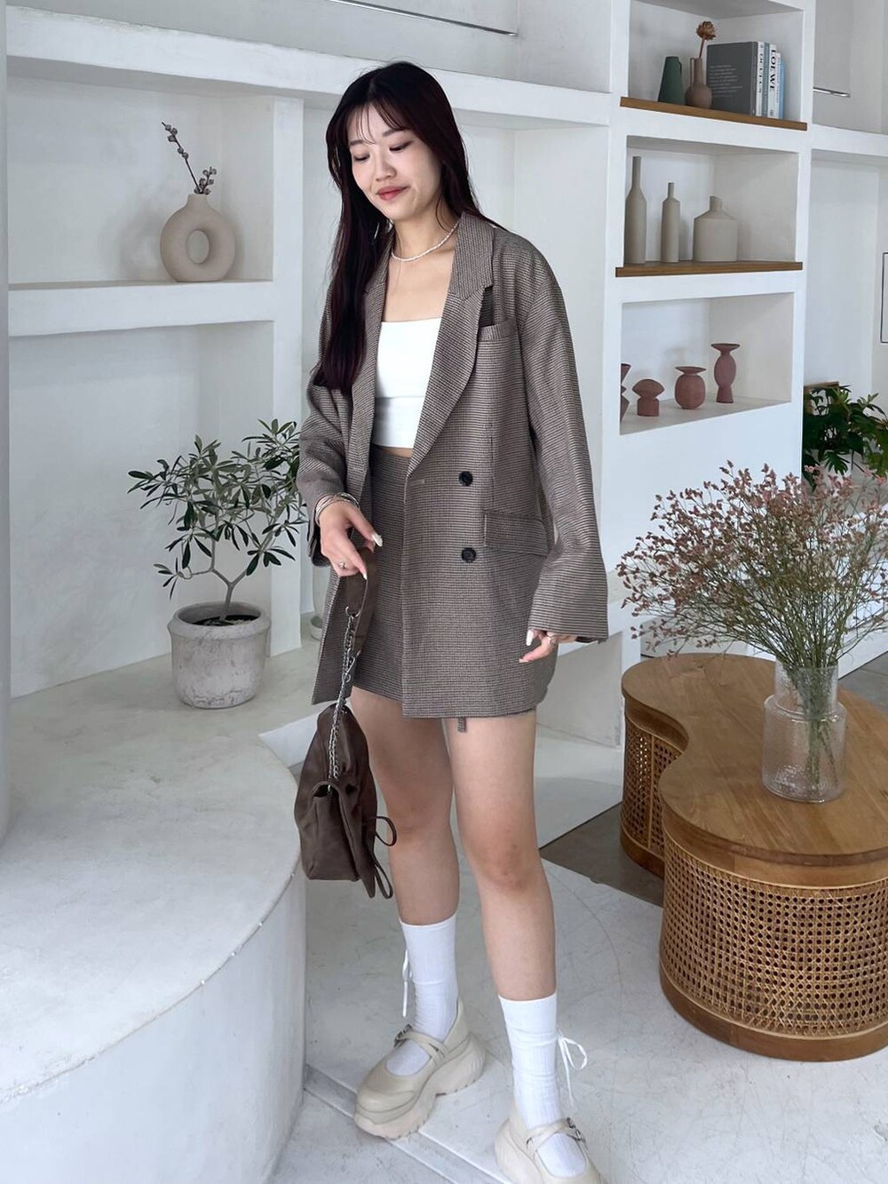 ブラウン系のショルダーバッグ、ホワイト系のキャミソール、ベージュ系のテーラードジャケットを着用したレディースの秋コーディネートの3枚目の写真