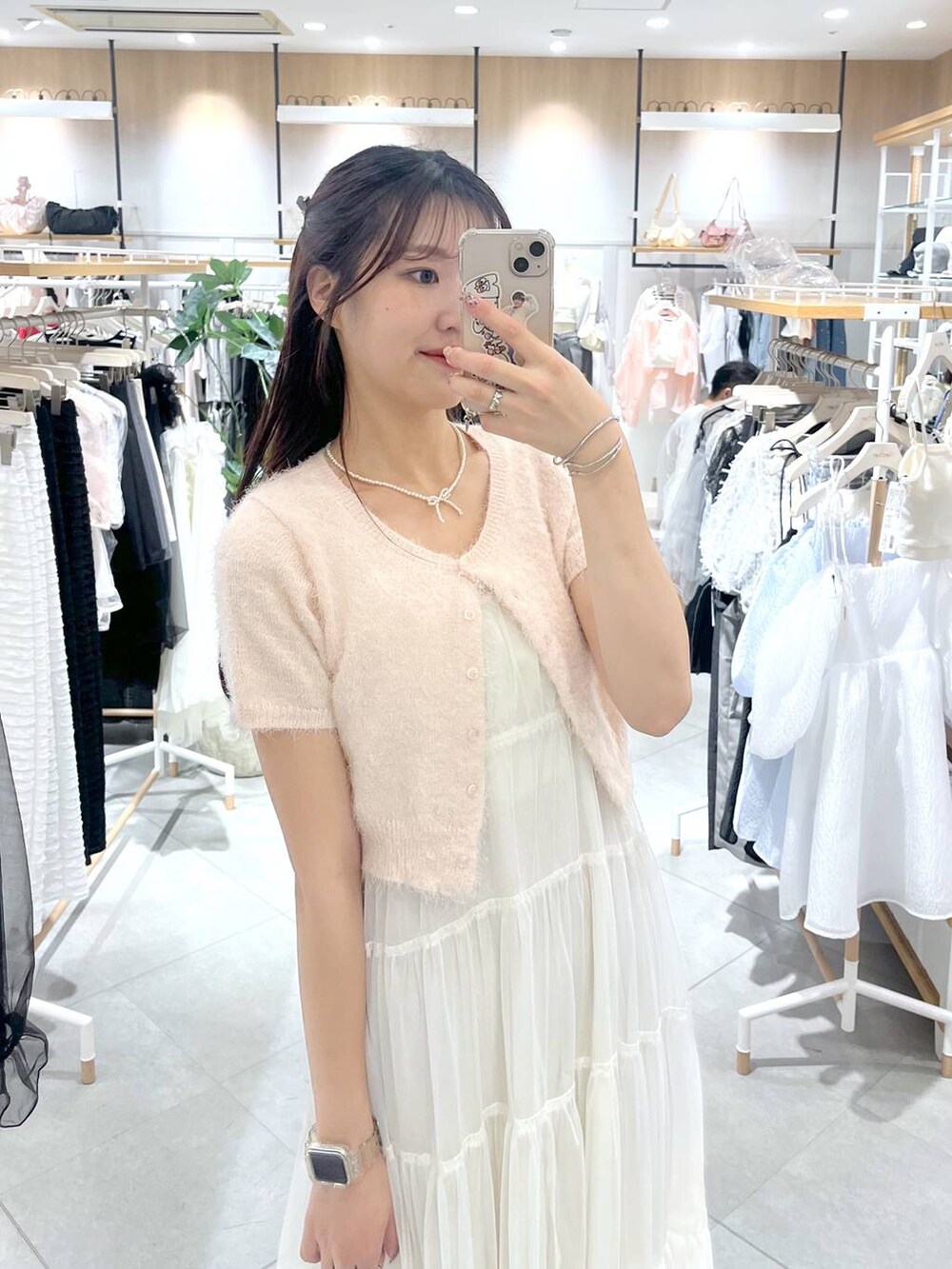 ホワイト系のワンピース、ピンク系のカーディガン/ボレロ、ブラック系のサンダルを着用したレディースの春コーディネートの2枚目の写真