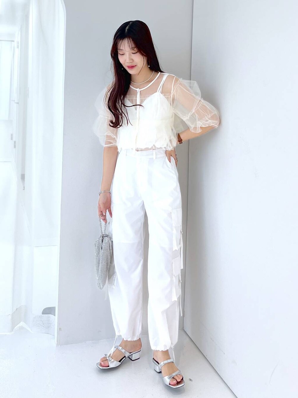 シルバー系のショルダーバッグ、ホワイト系のキャミソール、ホワイト系のベストを着用したレディースの夏コーディネートの6枚目の写真