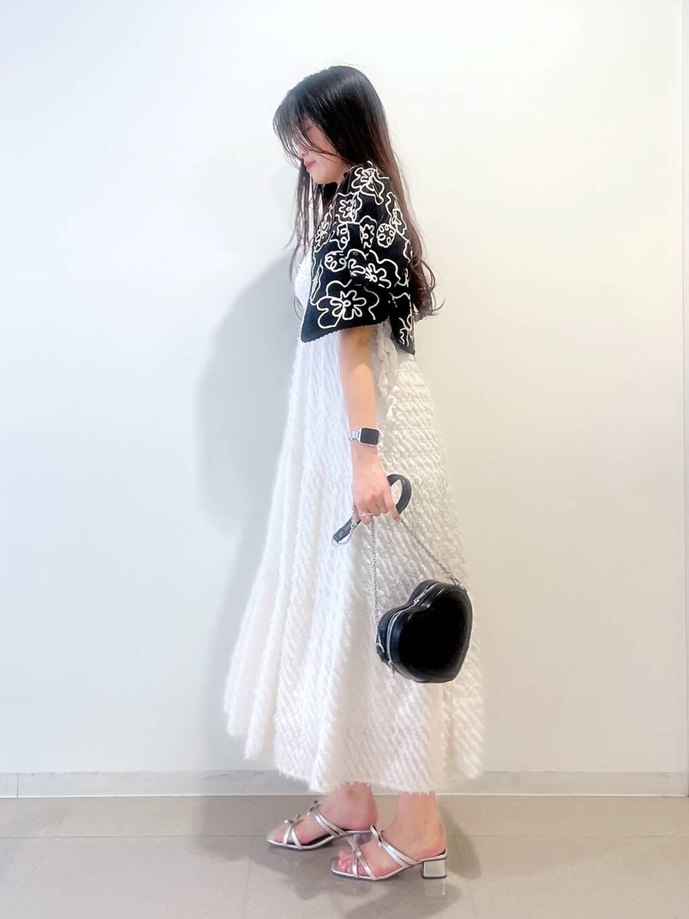 シルバー系のサンダル、ホワイト系のワンピース、ブラック系のショルダーバッグを着用したレディースの春コーディネートの4枚目の写真